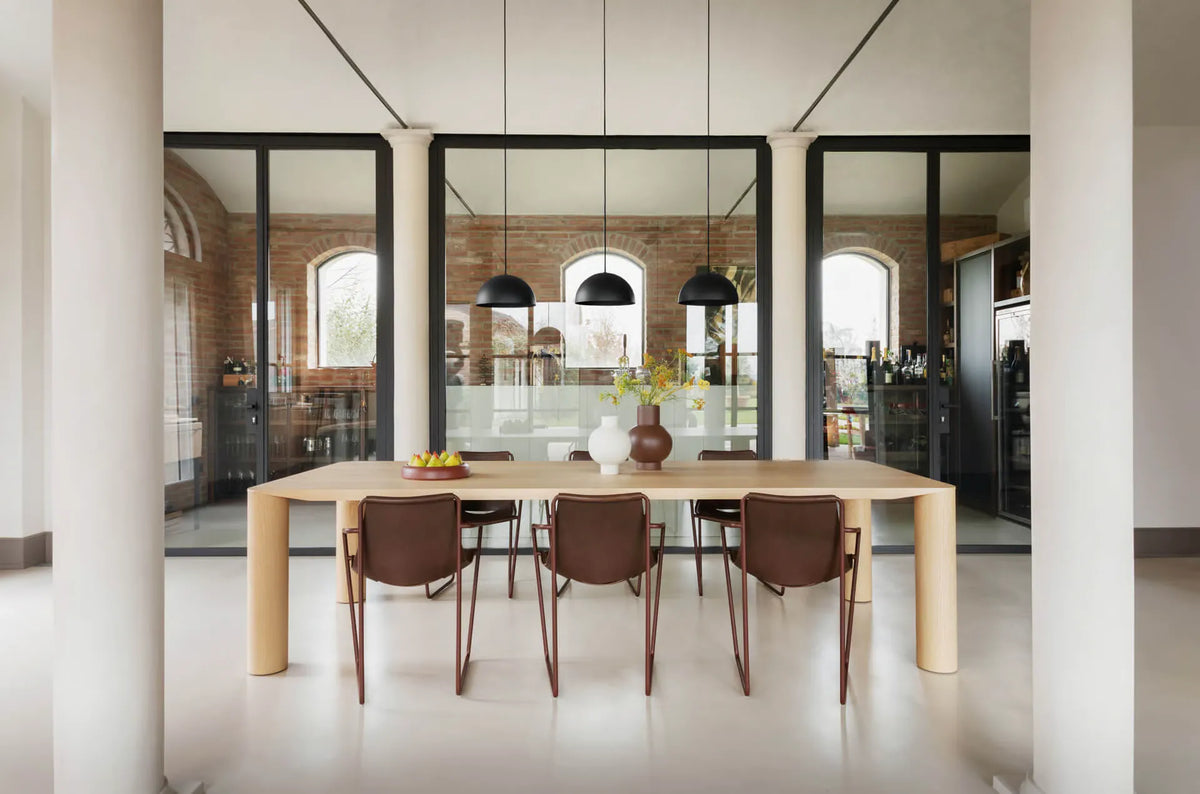Modern dining area with a long wooden table and chairs in a stylish interior.